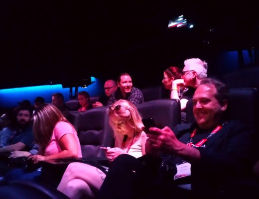 Audience in a screening room, many staring at cellphones.
