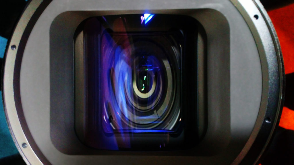 Front view of an anamorphic lens with the internal elements visibly distorted by the cylindrical front element.