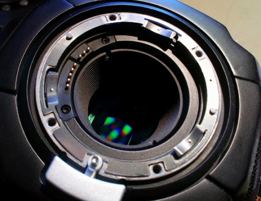 The lens port on a digital camera, with the sensor visible inside, creating colourful interference patterns.