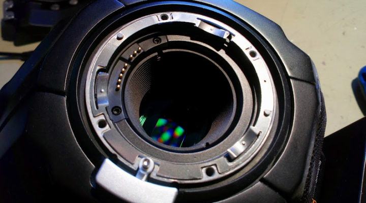 The lens port on a digital camera, with the sensor visible inside, creating colourful interference patterns.