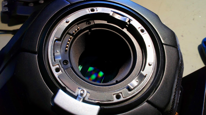 The lens port on a digital camera, with the sensor visible inside, creating colourful interference patterns.