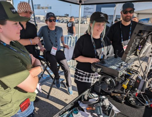 A young woman operating the handwheels on a remote head controller, surrounded by fellow students.