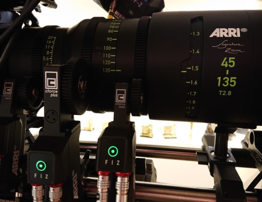 Three focus motors with their gears engaged with a large cinema zoom lens
