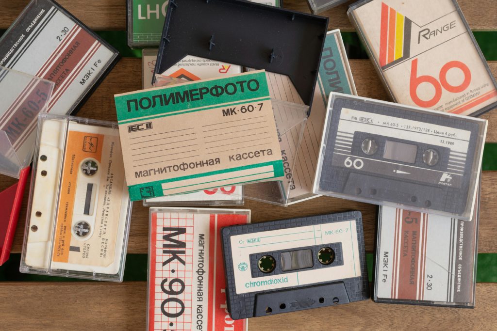 A pile of compact cassette tapes, some cased, some not, many with cyrillic lettering.