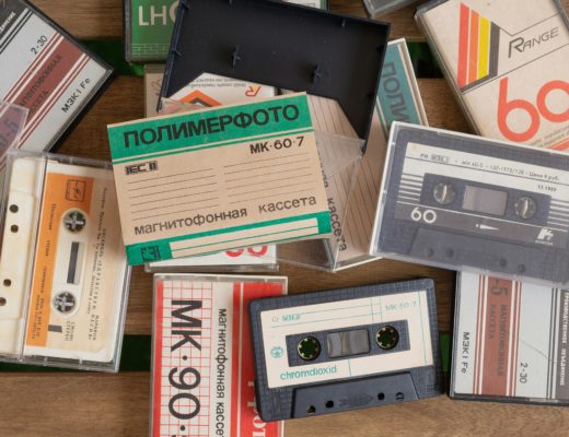 A pile of compact cassette tapes, some cased, some not, many with cyrillic lettering.