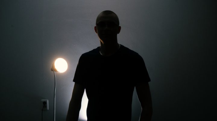 Man in a T-shirt silhouetted against a light.