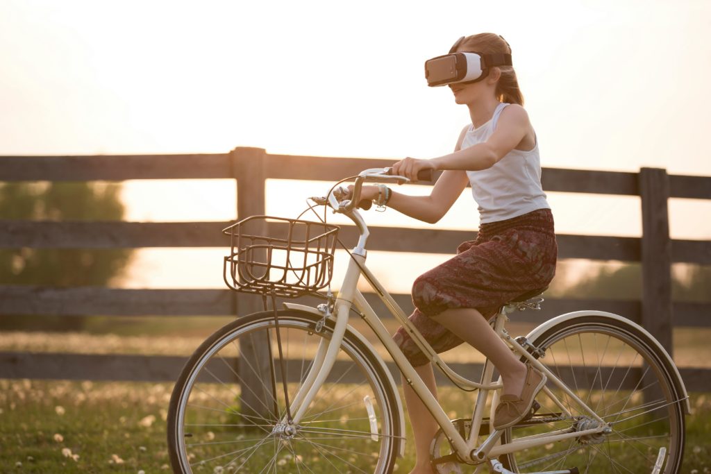 A woman on a bicycle wearing a virtual reality headset.
