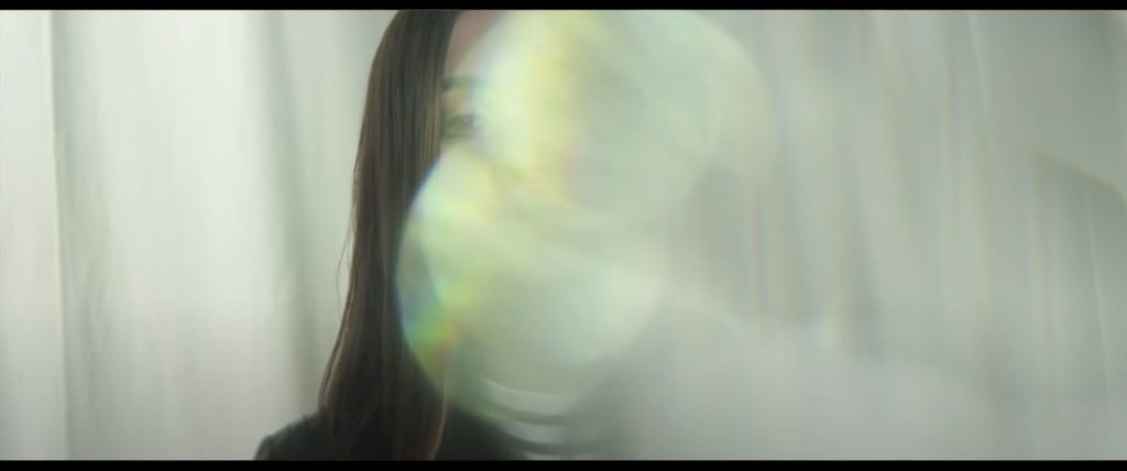 A young woman's face is almost completely obscured by a bright optical effect