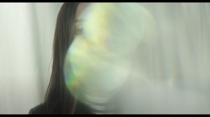 A young woman's face is almost completely obscured by a bright optical effect